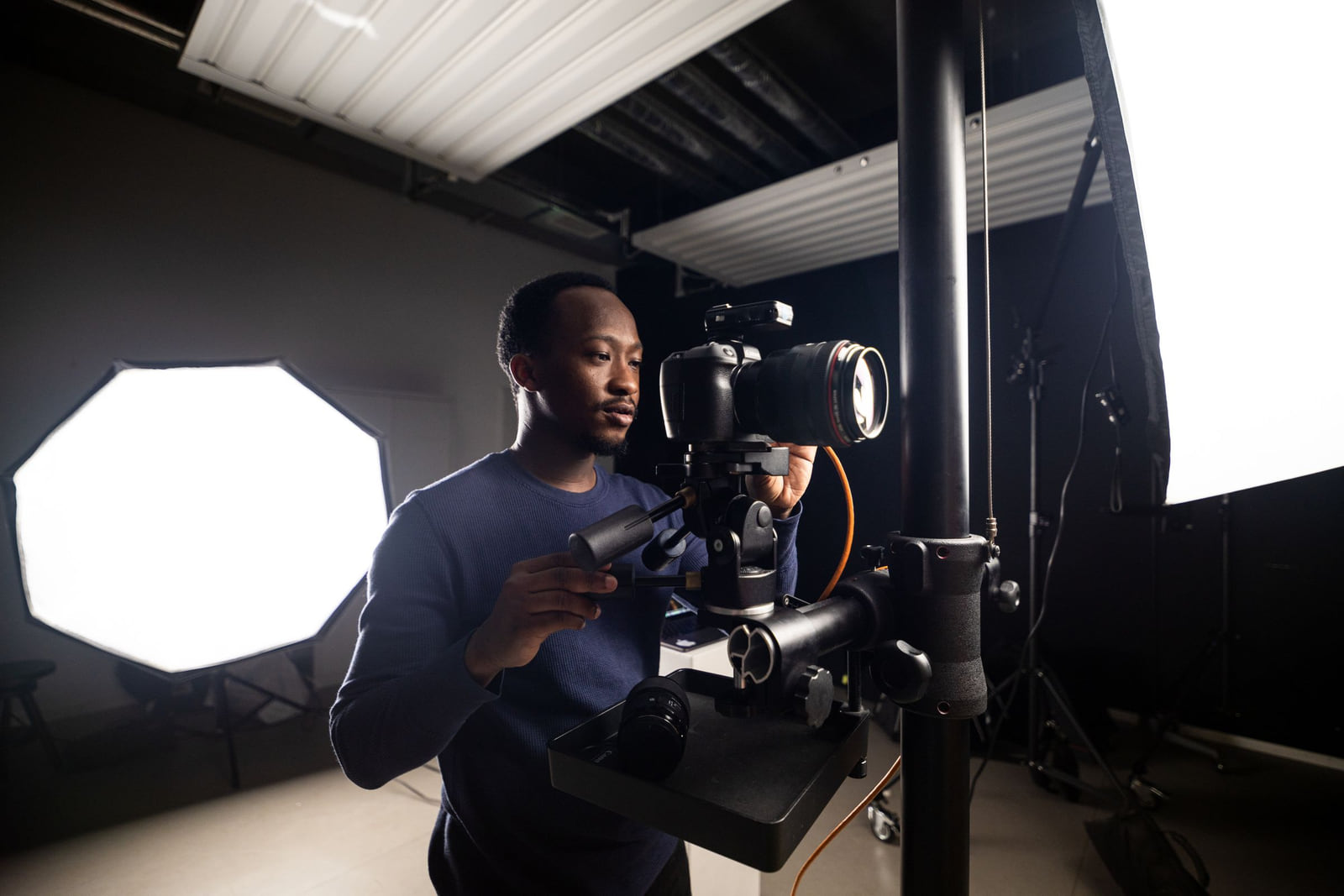 A photographer adjusting a professional camera in a studio.