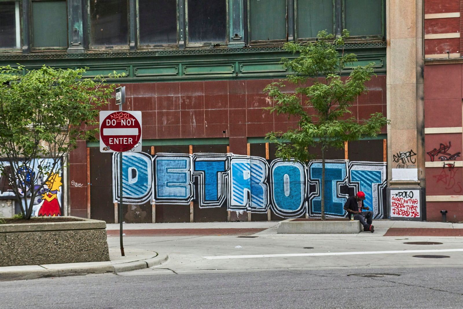 A Detroit street corner with a large Detroit mural on a brick building.