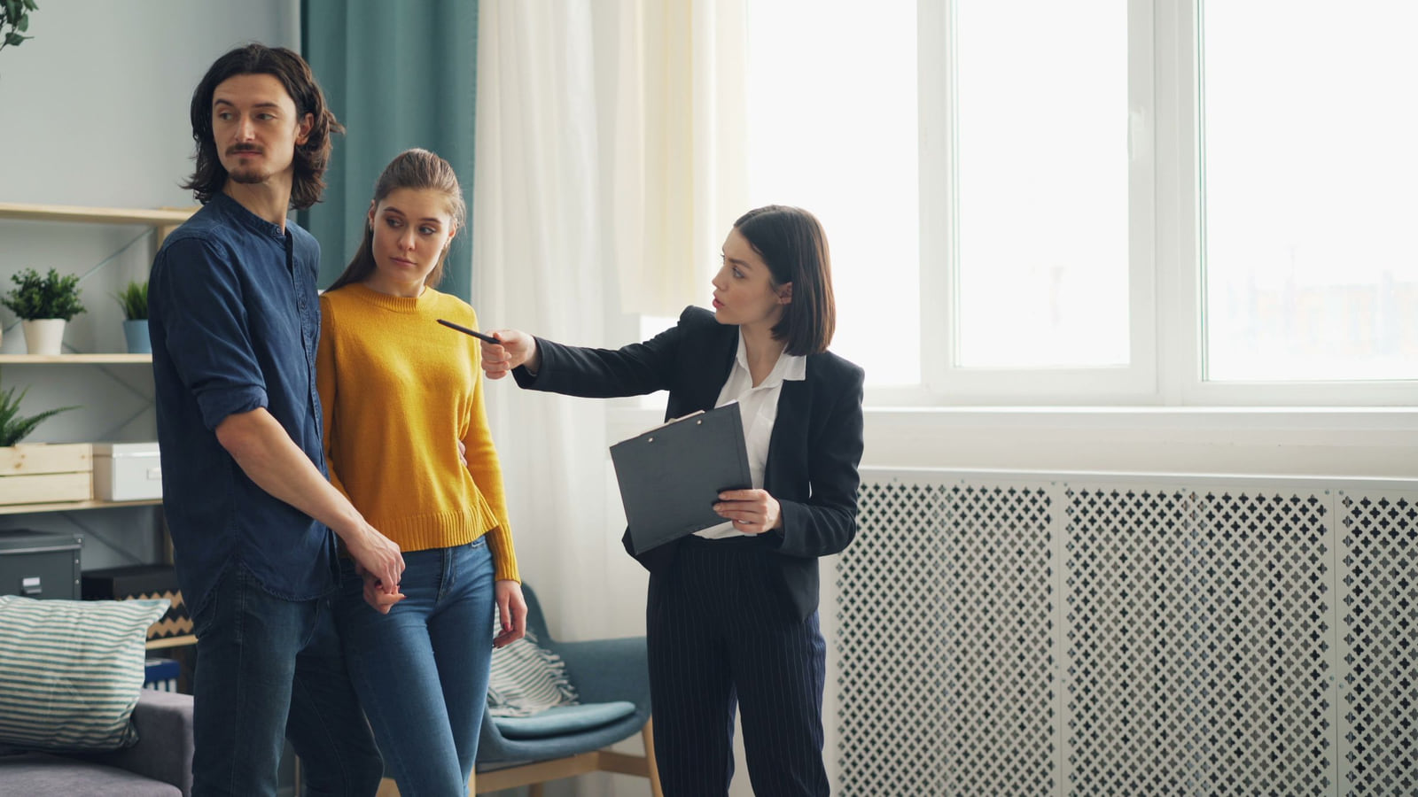 A real estate agent discussing a room with a couple during a home viewing.