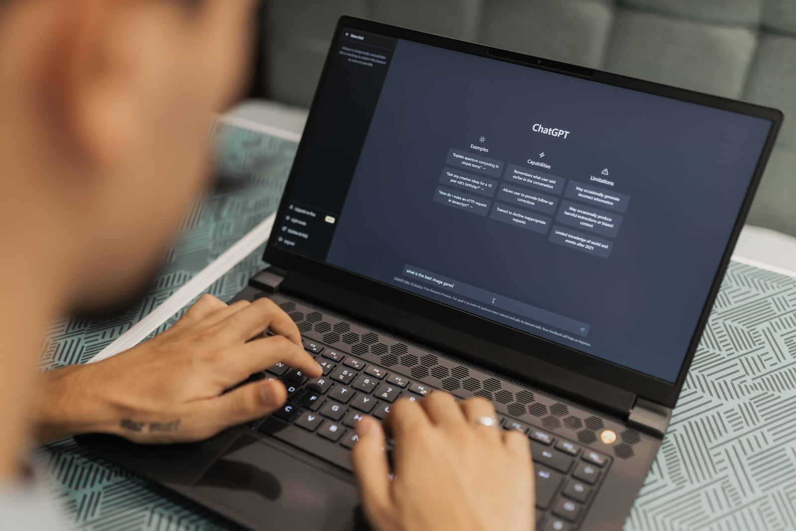 Hands using a laptop with the ChatGPT interface displayed.