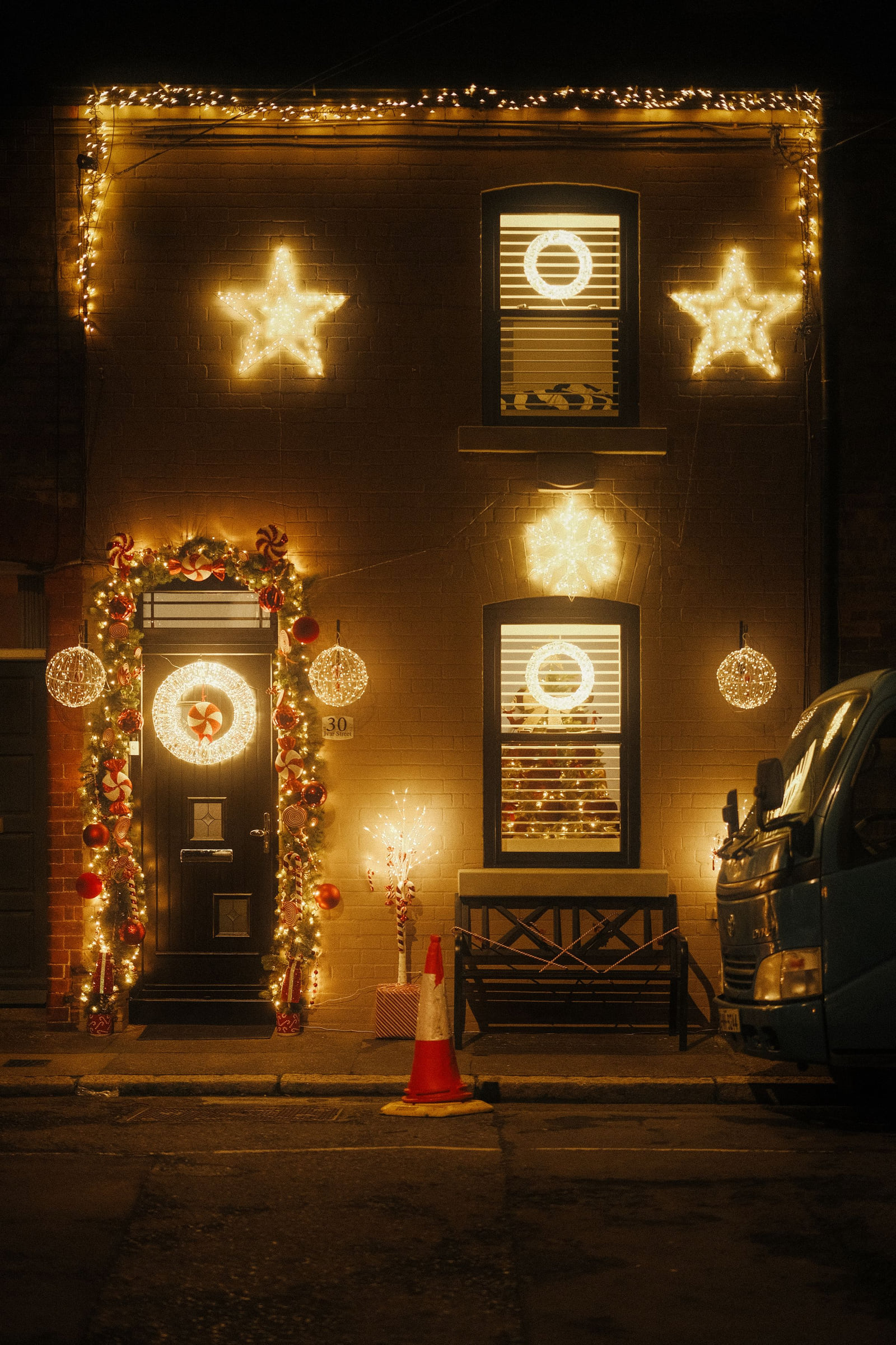 A house entrance decorated with warm Christmas lights after dark.