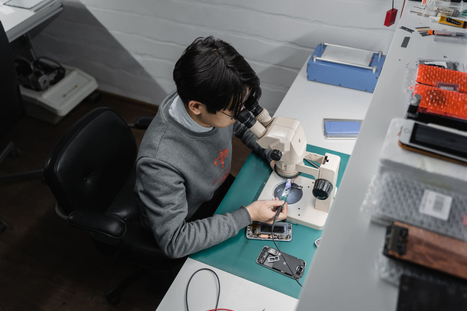A technician working on a smartphone at an electronics repair bench.