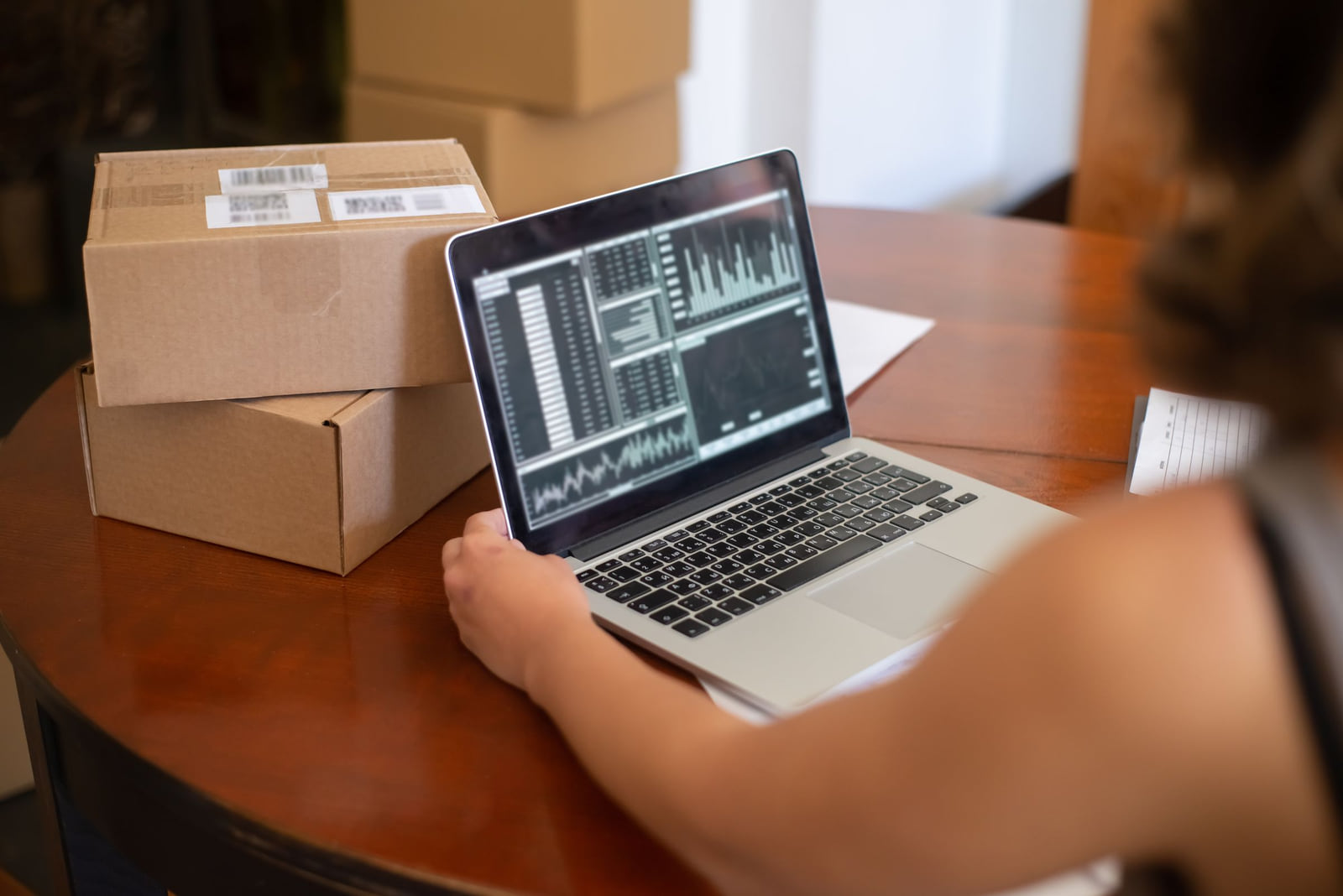 A business owner checking a laptop beside packed orders.