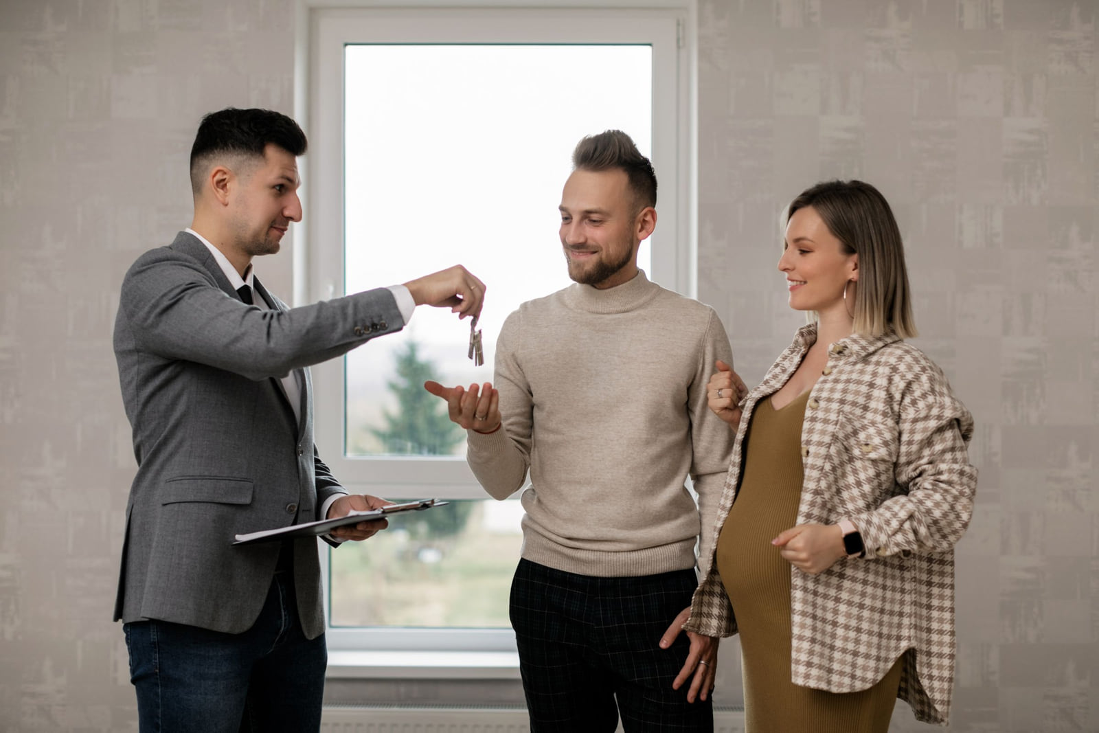 A real estate agent presenting keys to a couple.