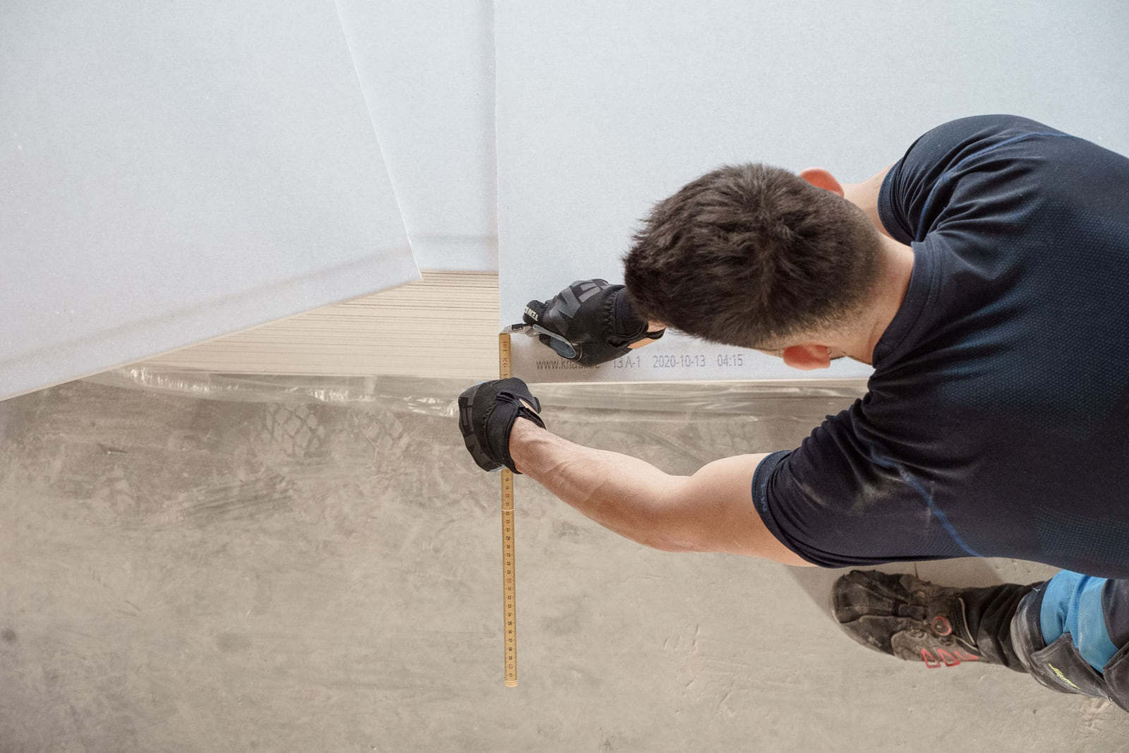 A worker measuring a floor during installation work.