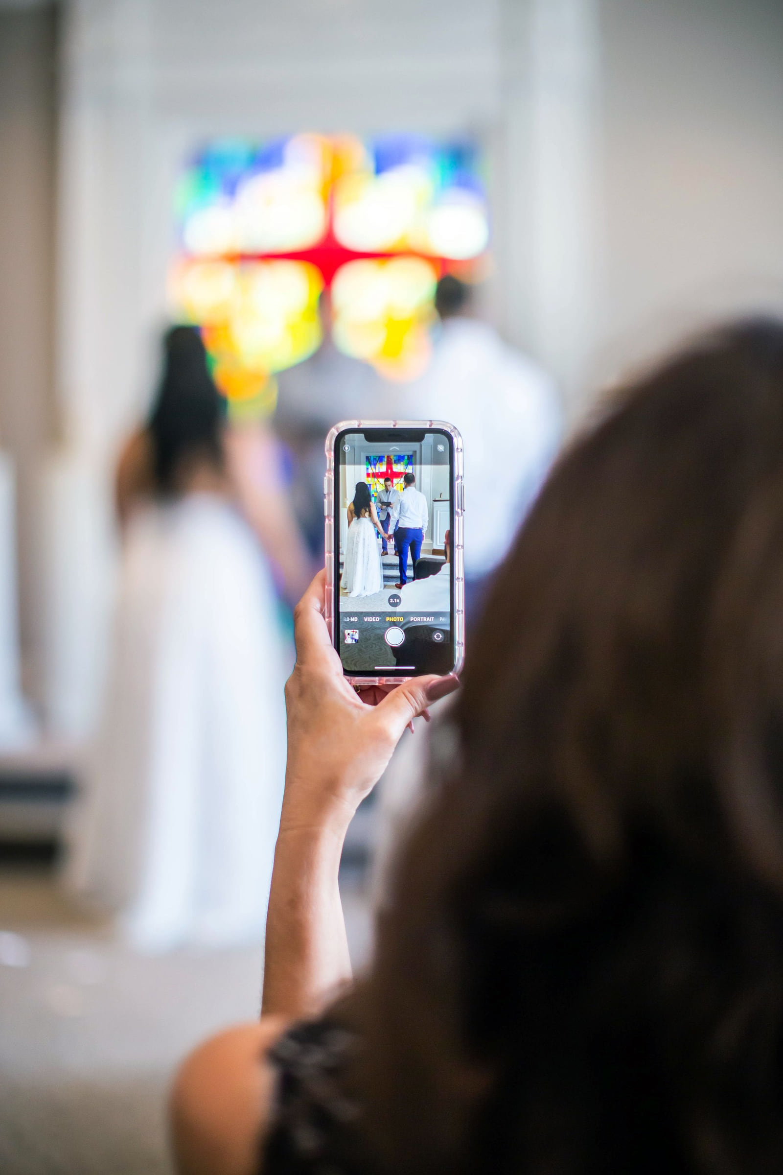 A guest holding up a phone to photograph a wedding ceremony.