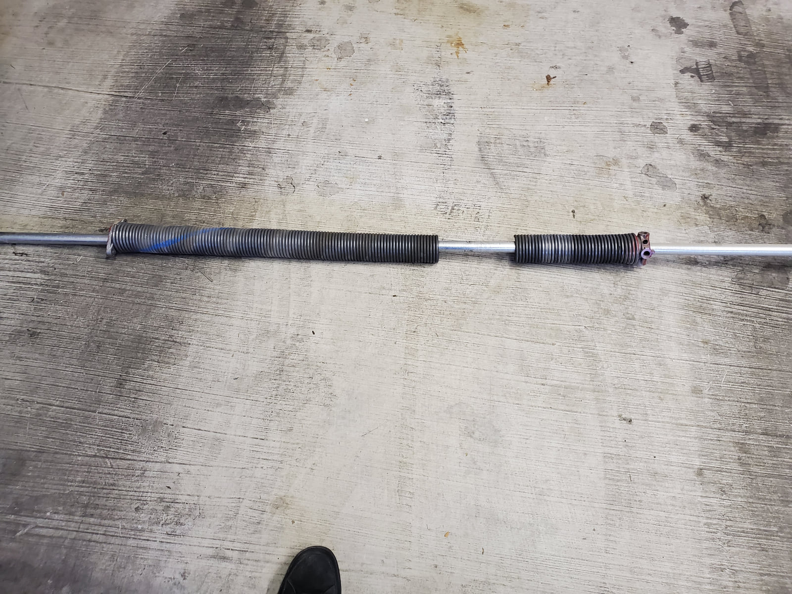 Broken garage-door torsion springs laid out on concrete.