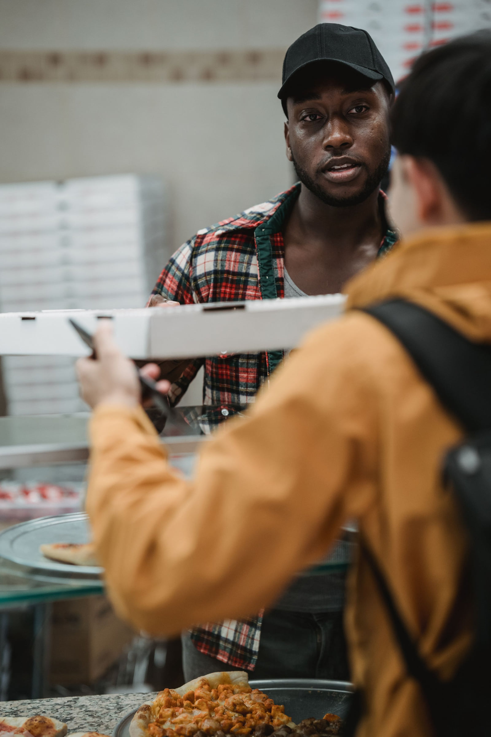 A customer speaking with an employee at a pizza counter.