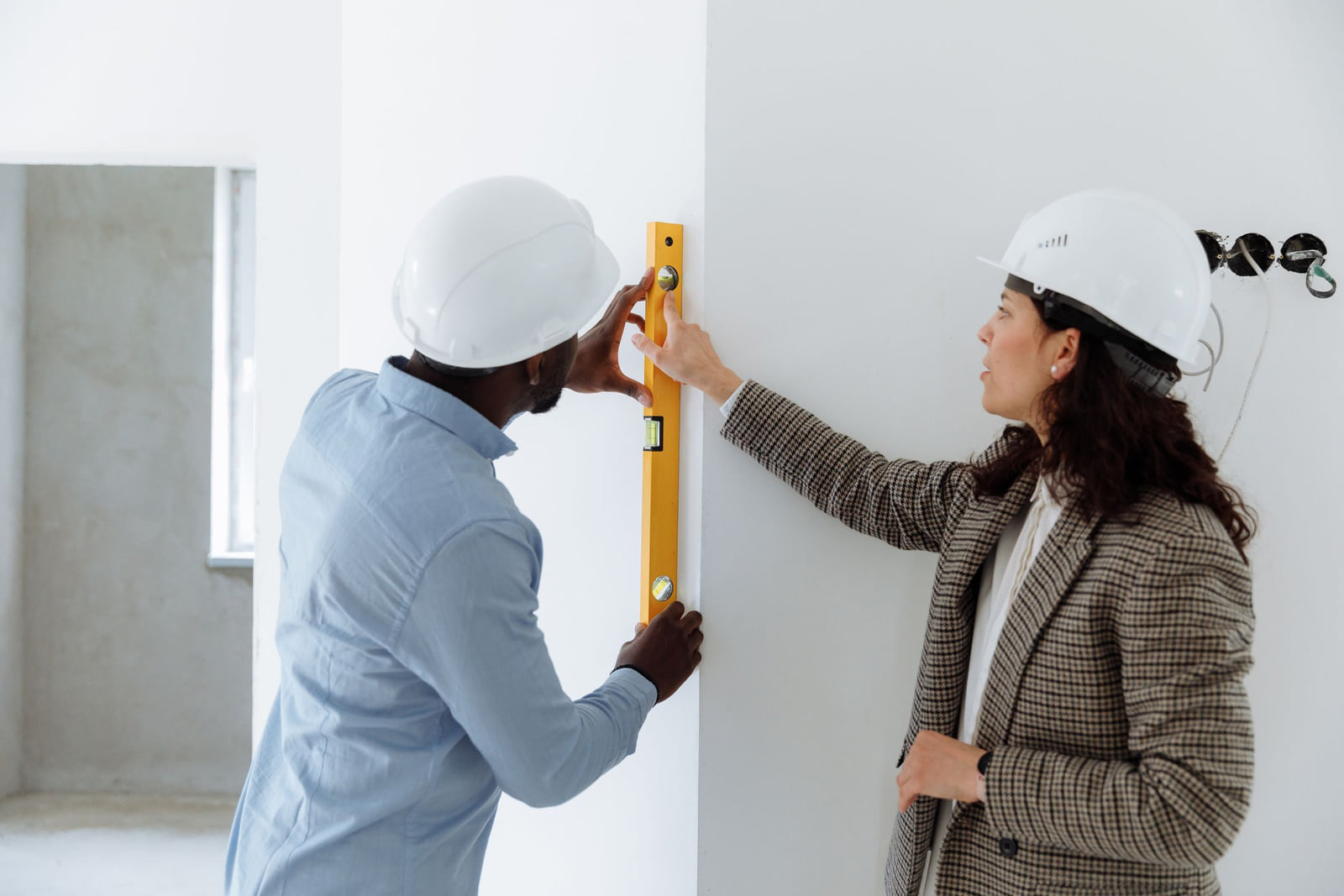 Two people checking a wall with a spirit level.