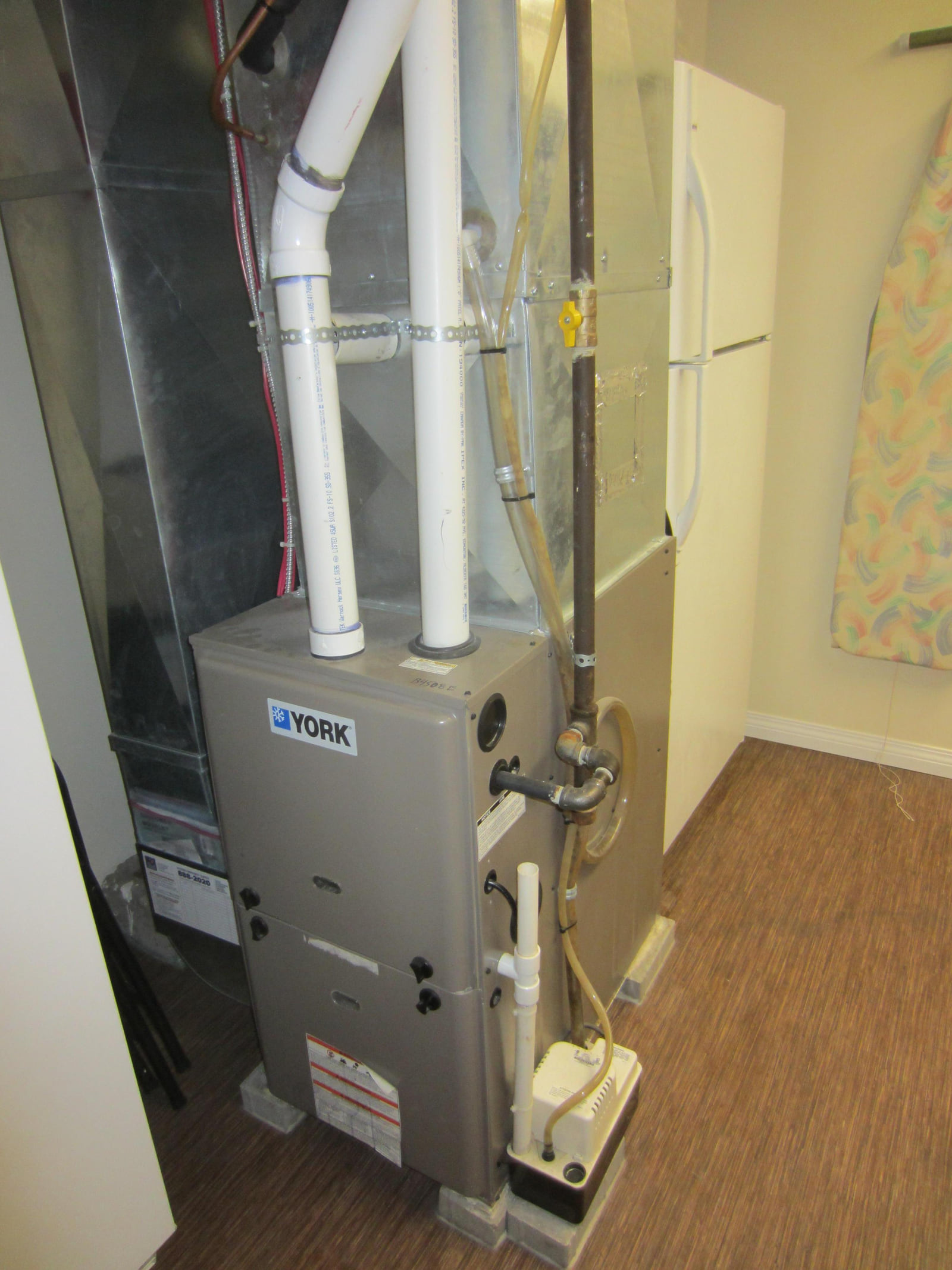 A residential forced-air furnace connected to ducts and vent pipes.