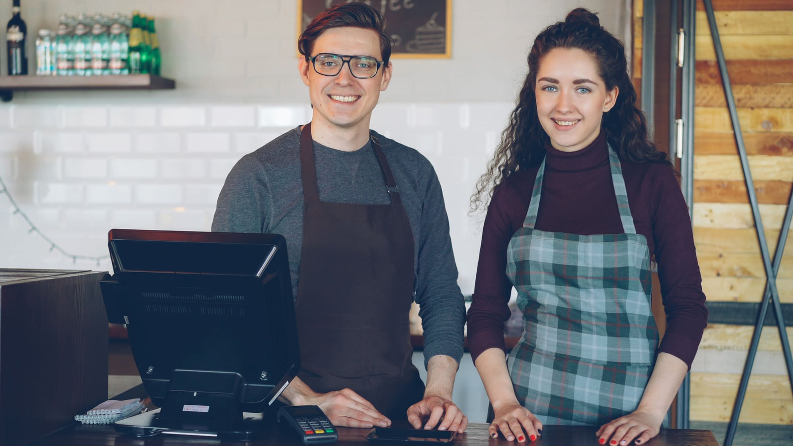 Two smiling café workers standing behind the counter.