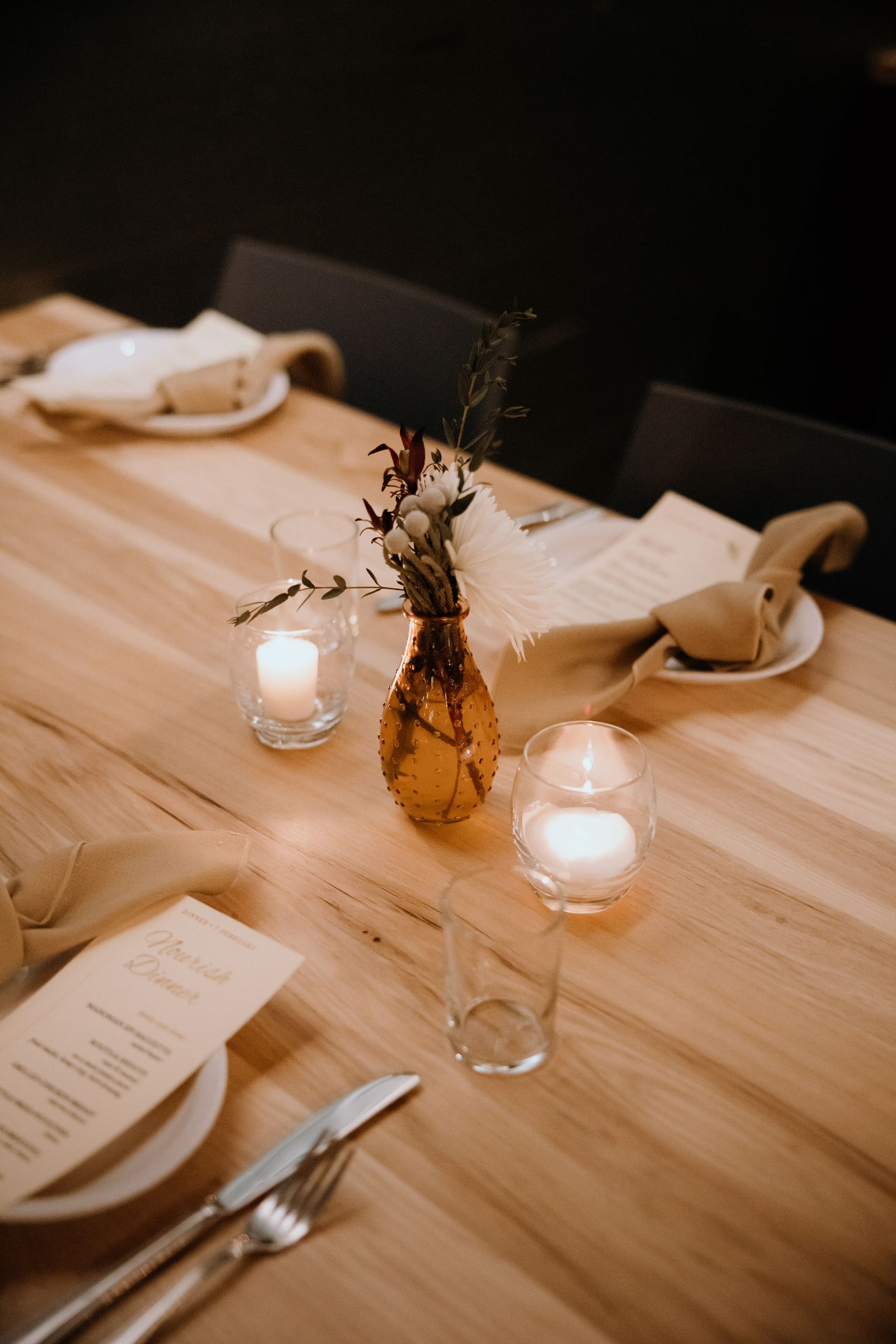 A restaurant table set with candles, glassware and place settings.
