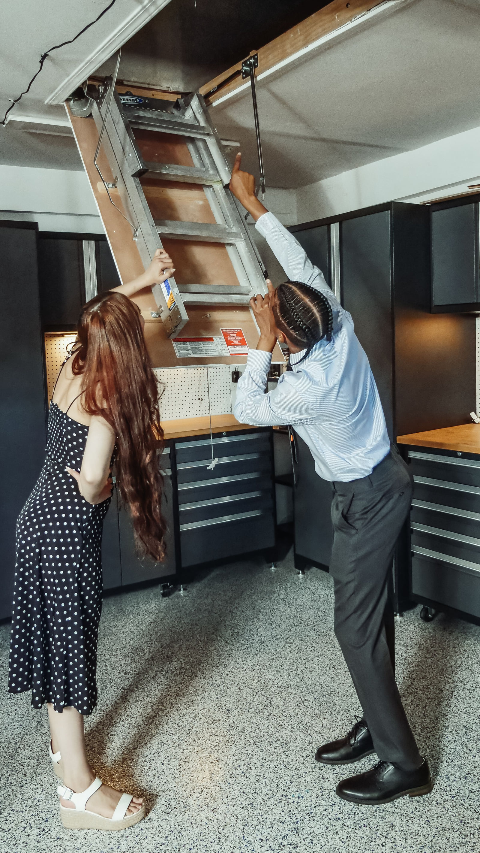 A property professional and a customer looking toward an attic opening.