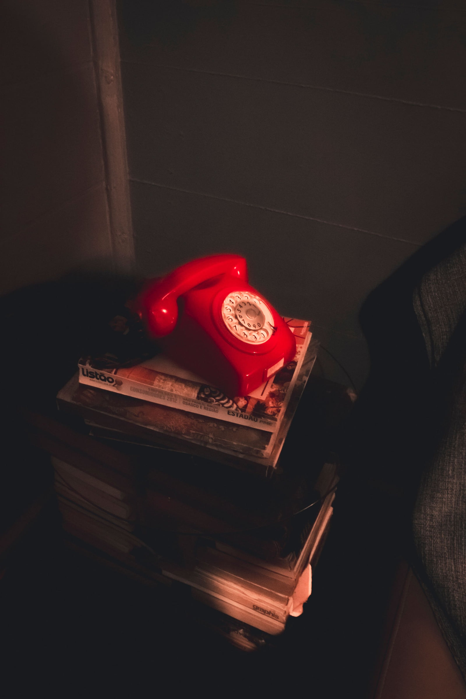 A red vintage telephone resting on a stack of books.