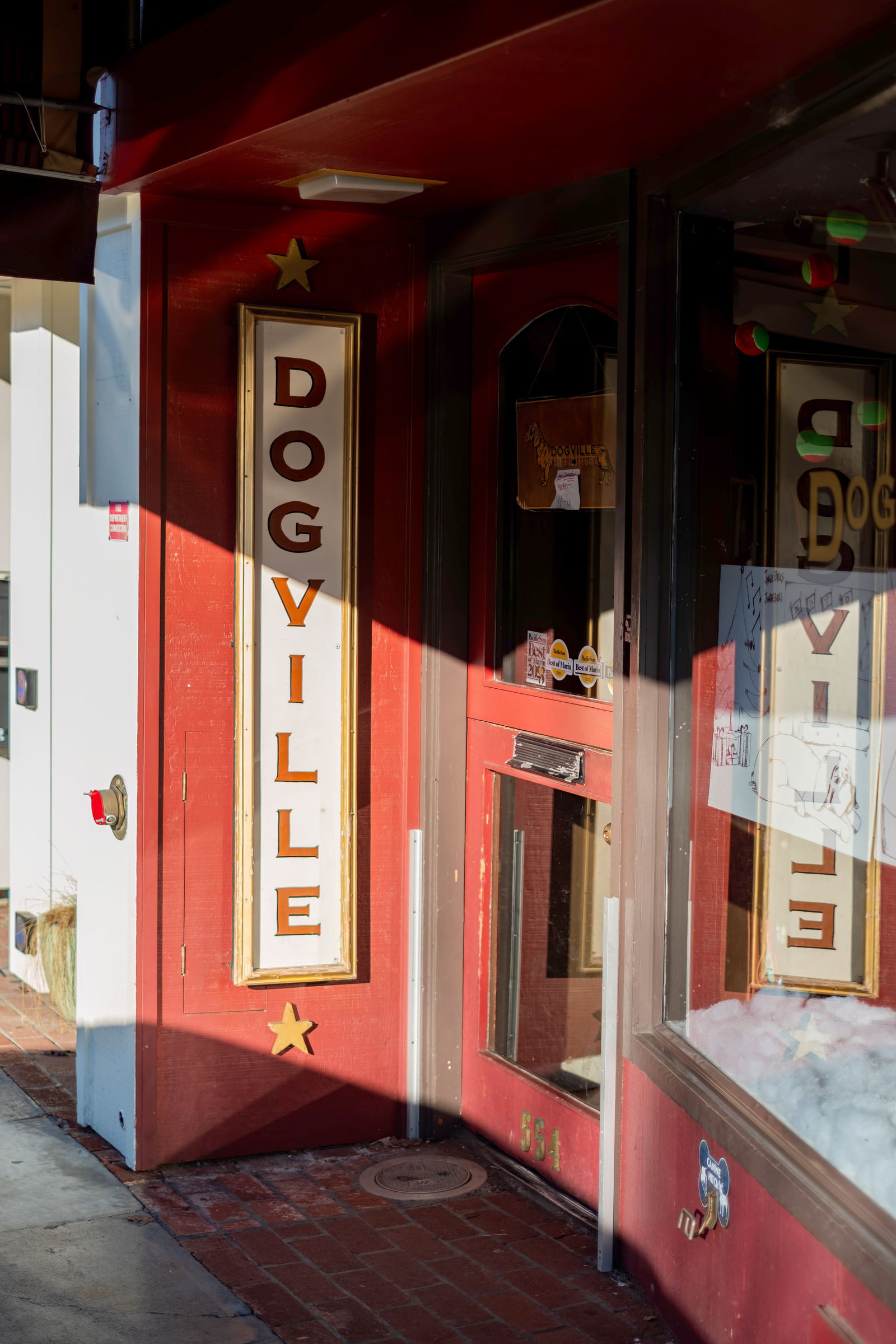The red entrance to Dogville pet shop with a dog looking through the doorway.
