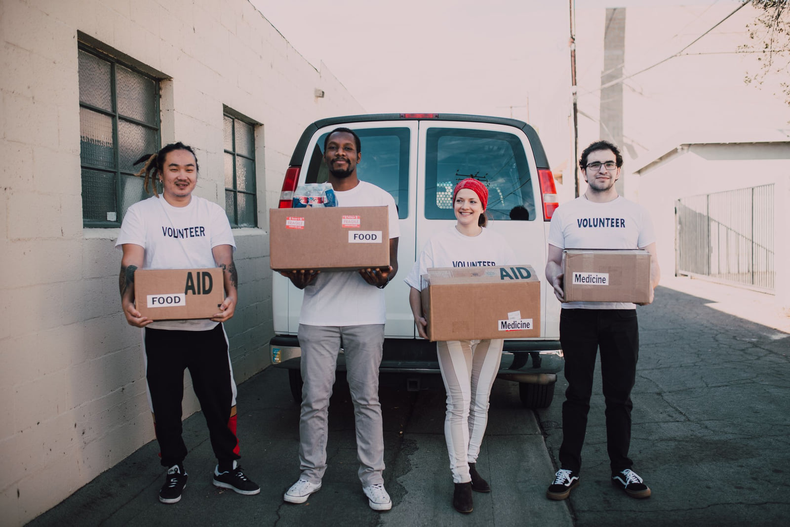 Volunteers standing beside a van with boxes of donated supplies.