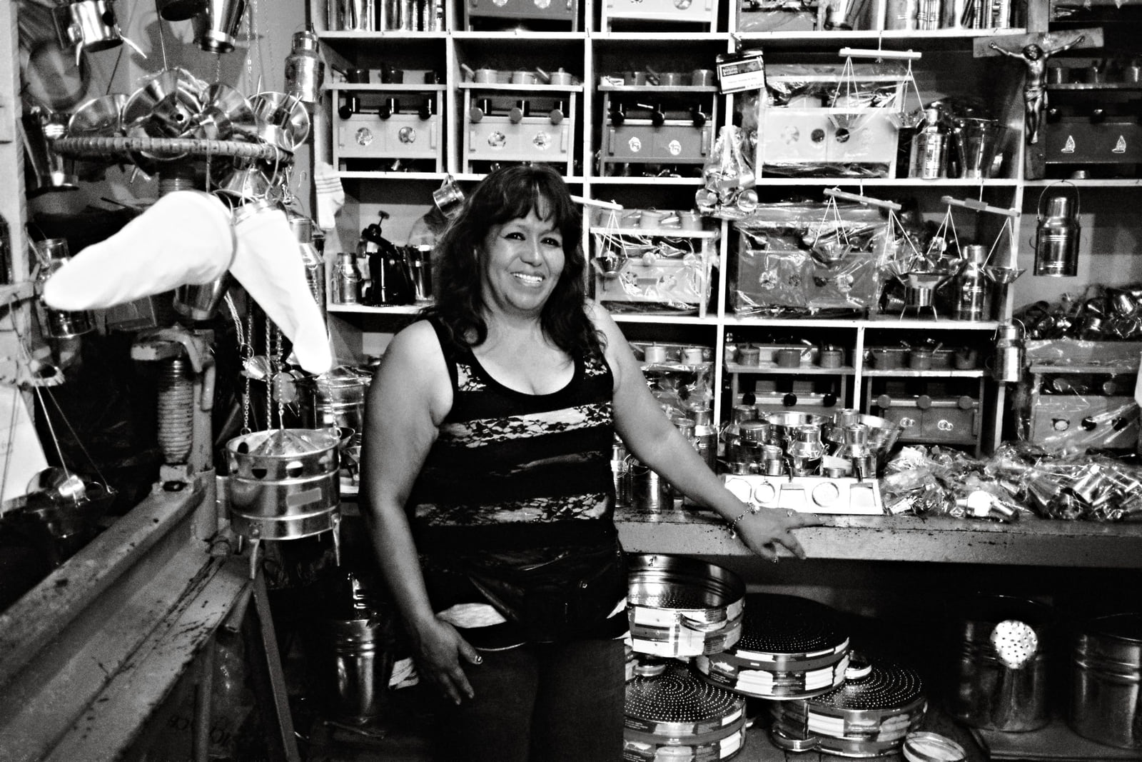 A shopkeeper standing among densely stocked shelves in a hardware shop.