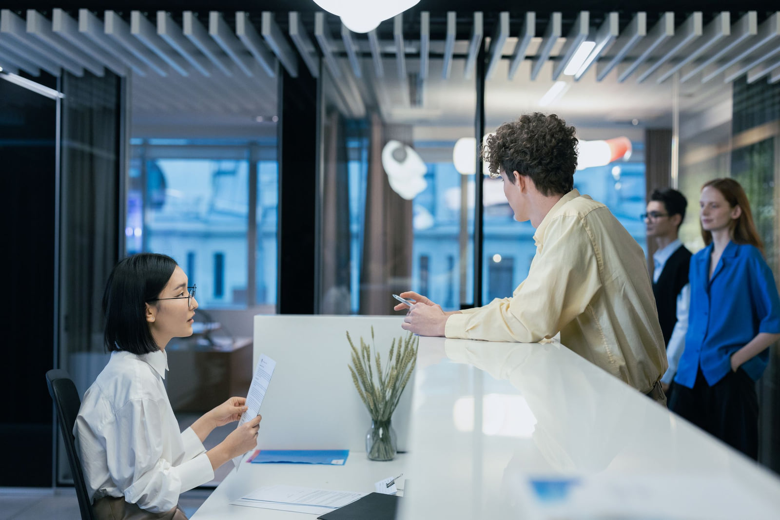 Visitors speaking with a receptionist at a modern office front desk.