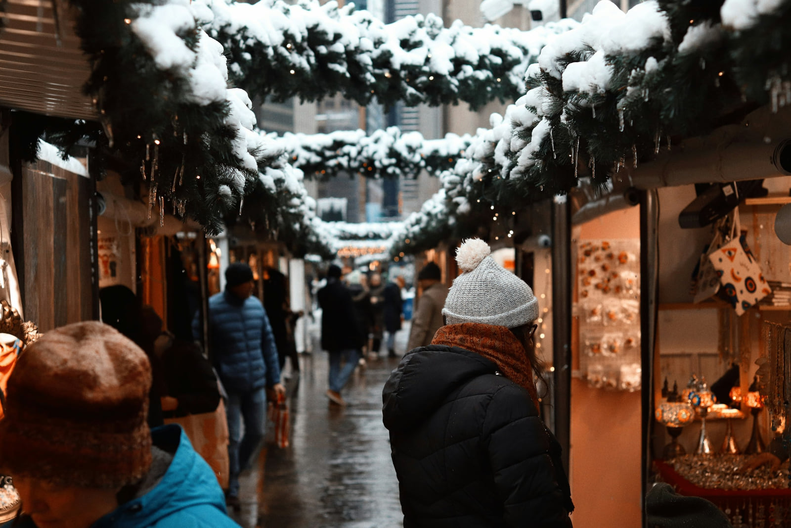 Shoppers walking through a snow-covered holiday market in New York.