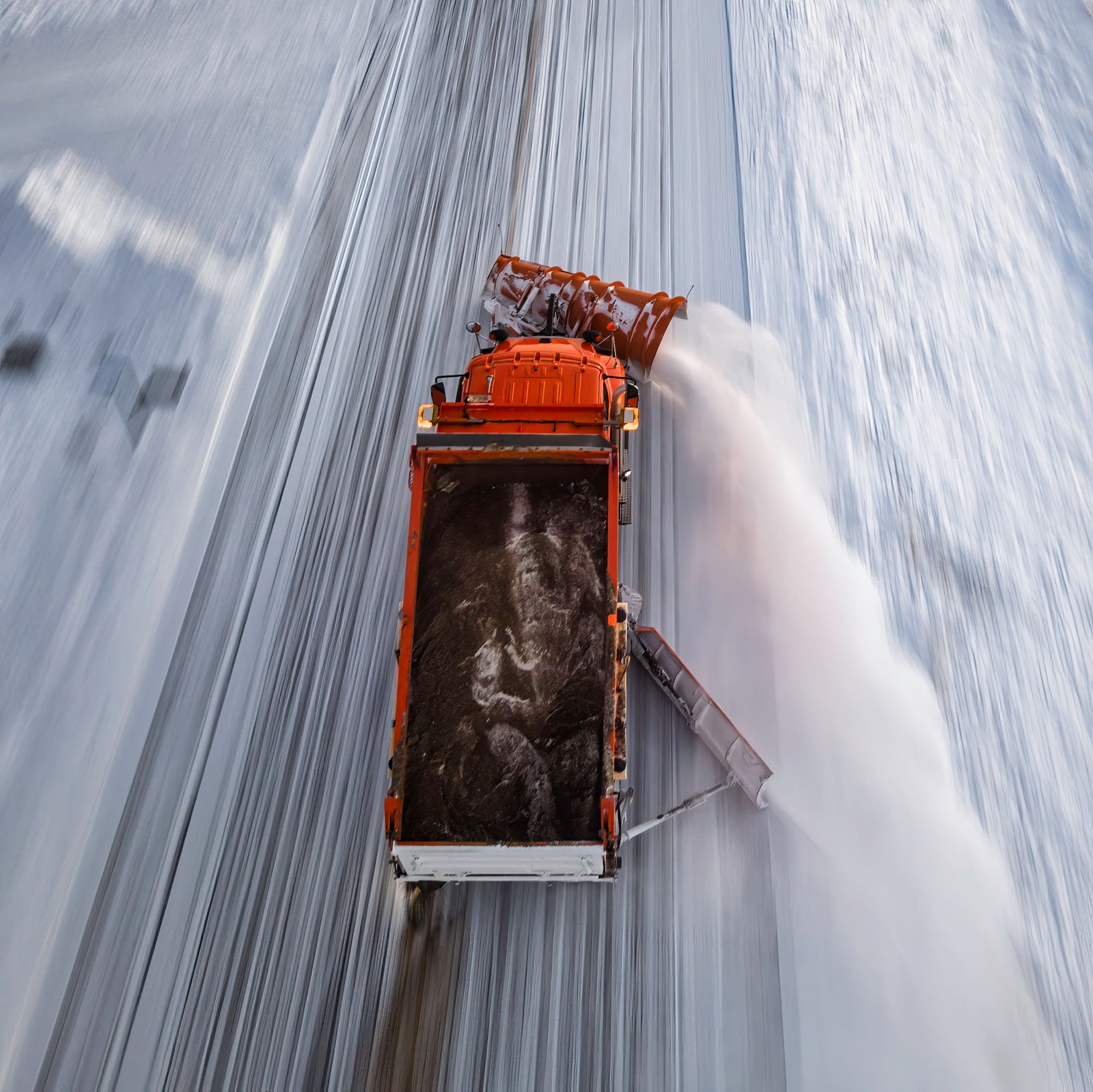 An overhead view of a snowplow clearing a snow-covered road.