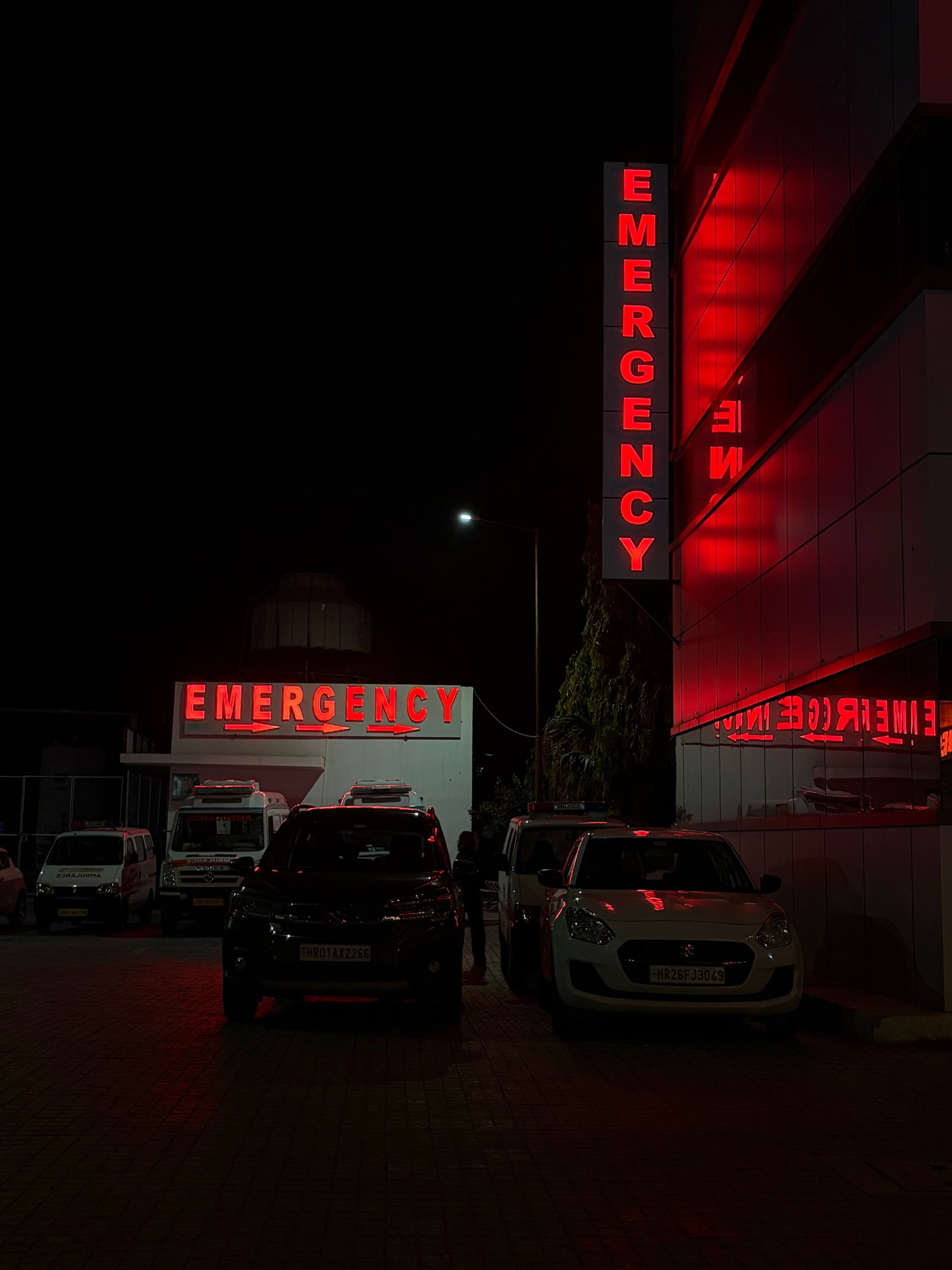 A hospital emergency entrance with illuminated red Emergency signs at night.