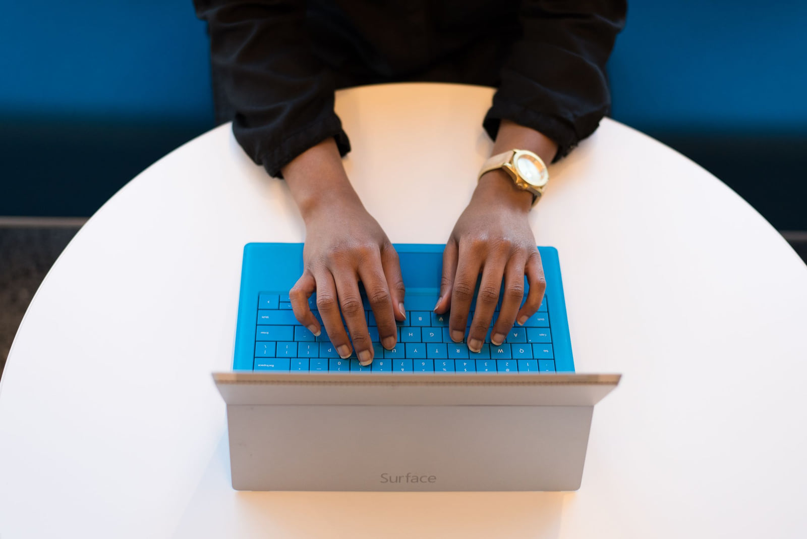 Hands typing on a laptop at a round white table.