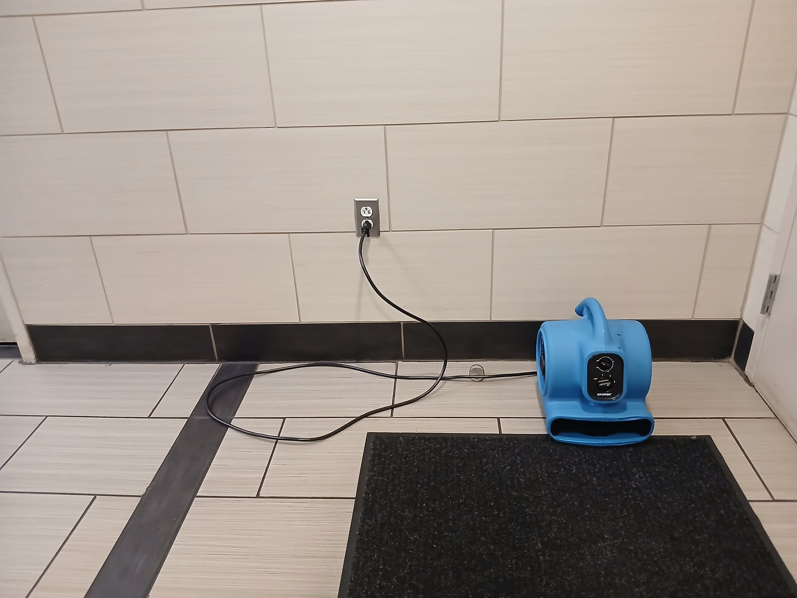 A portable air mover operating on a tiled floor.
