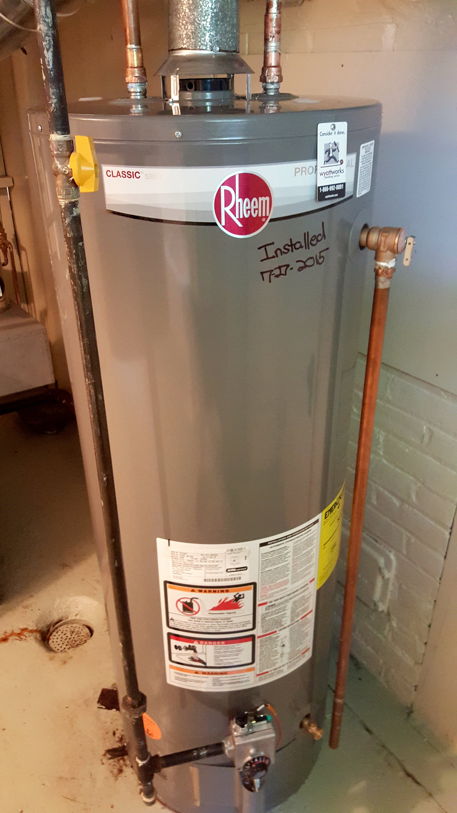 A newly installed residential gas water-heater tank and connected pipework.