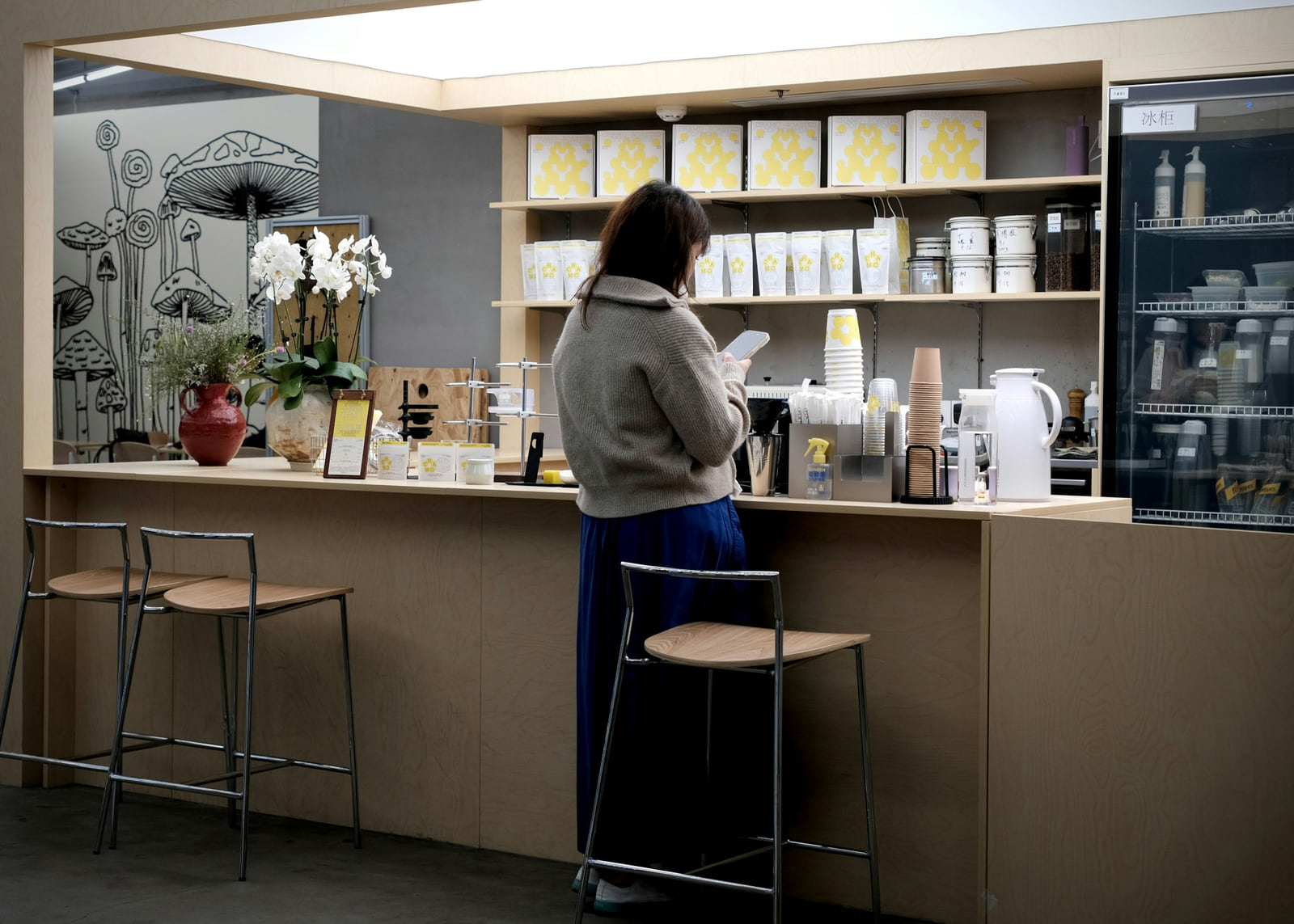 A customer checking her phone at a neighborhood café counter.