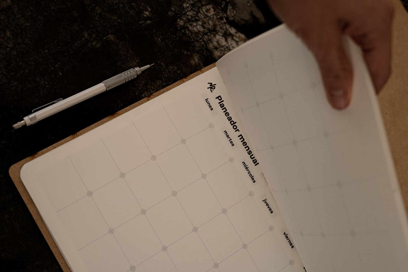 An open paper calendar with a person's hand holding the page.