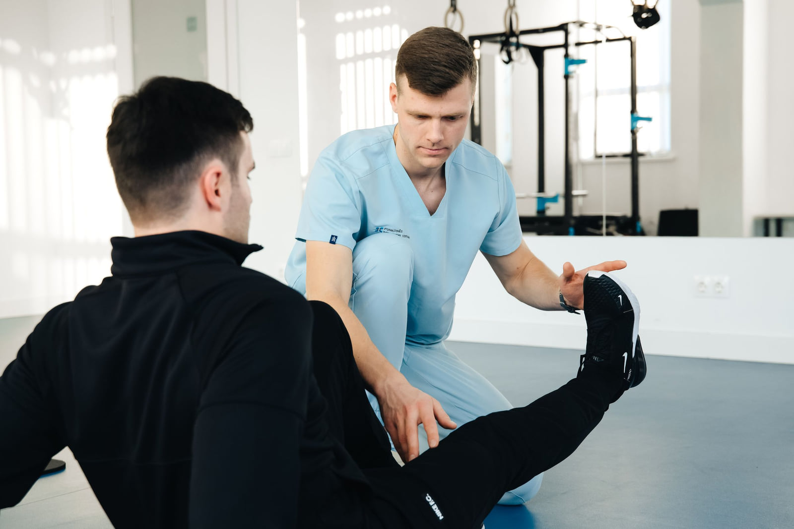 A physical therapist guiding a patient's leg during an exercise.