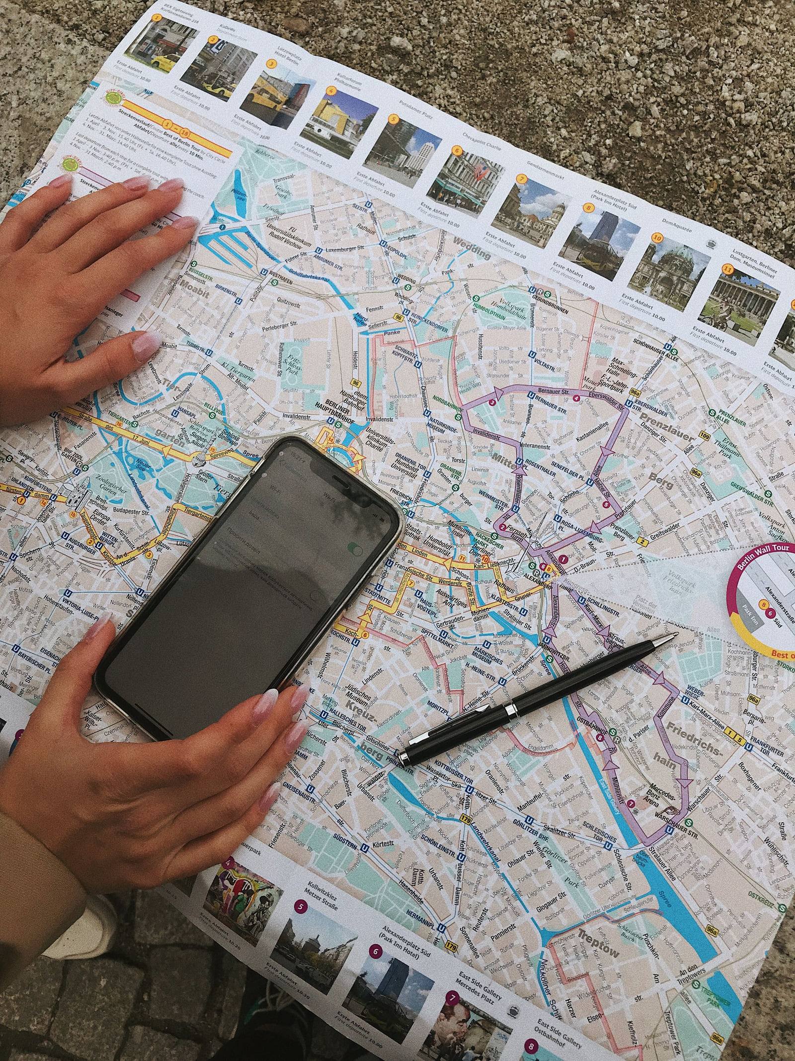 A smartphone and pen lying on an unfolded paper street map.