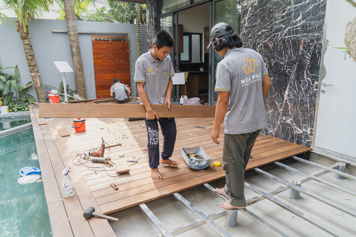 Workers fitting wooden floorboards during a construction project.
