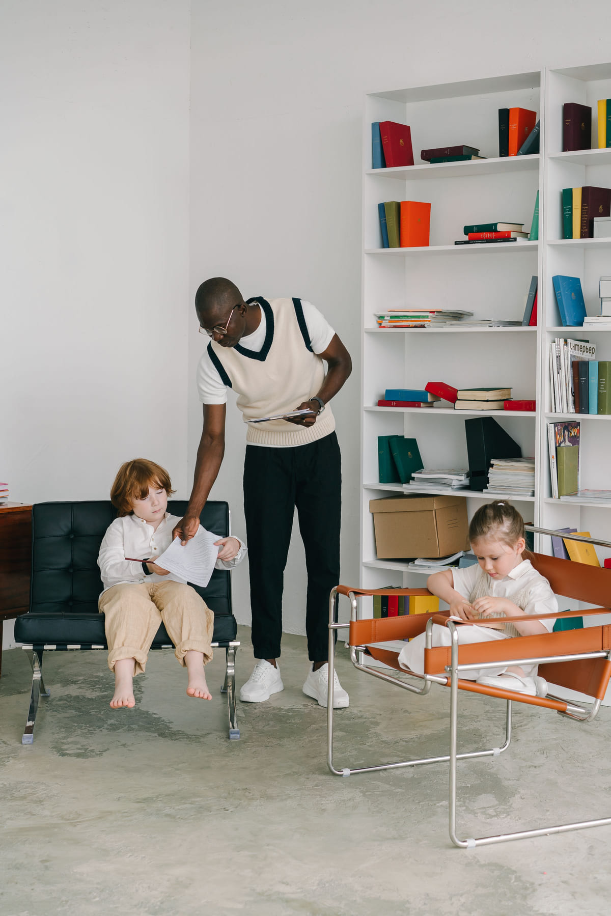 A practitioner guiding two children through an activity in a bright room.