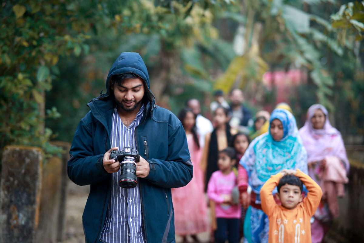 A photographer checking his camera during an outdoor family gathering.
