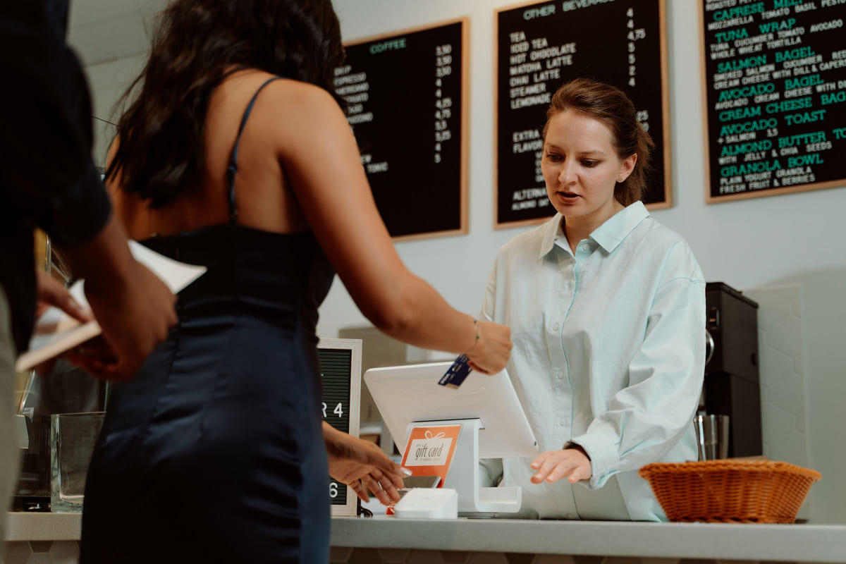 A café employee assisting a customer at the payment counter.