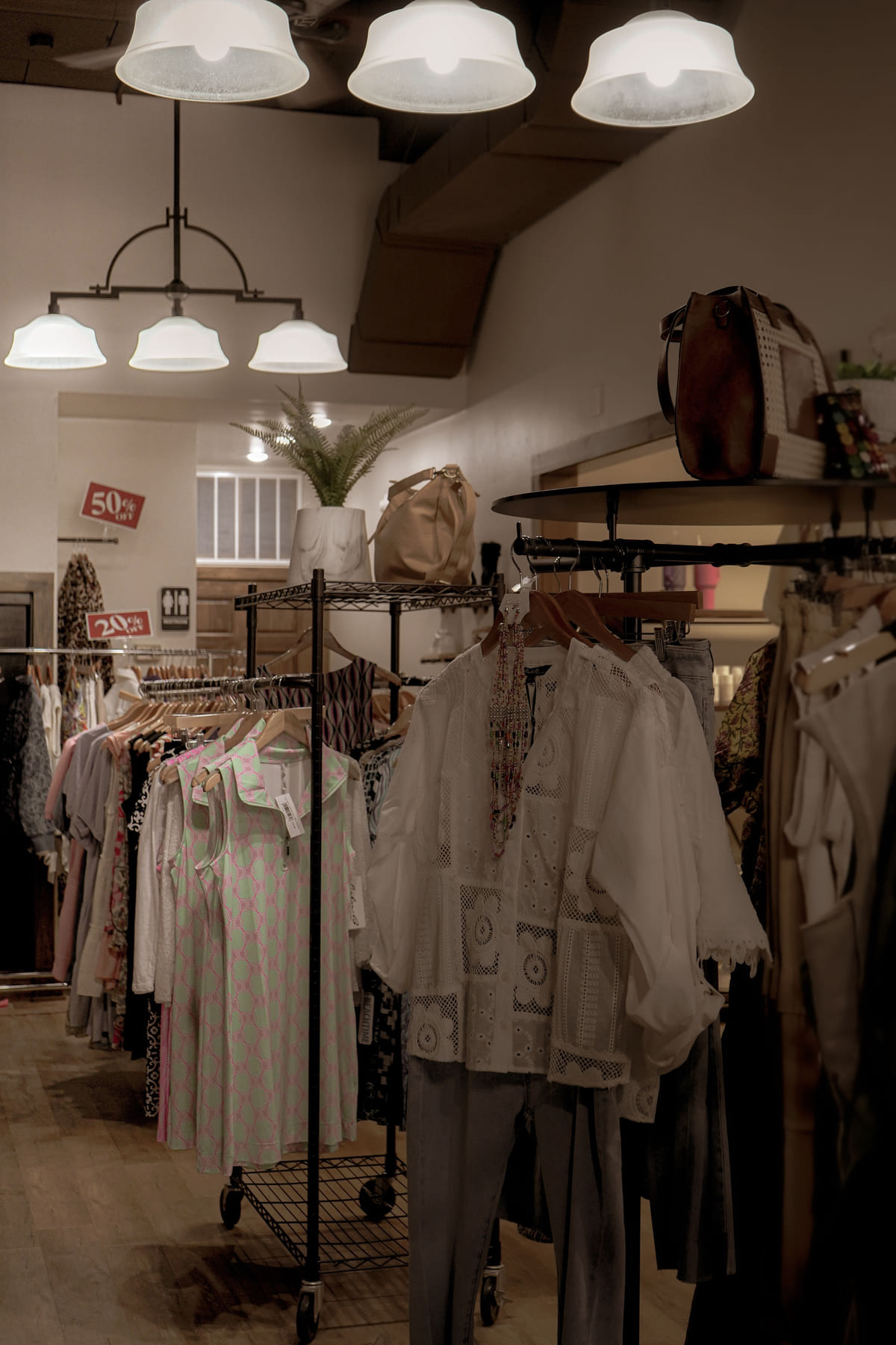 Clothing racks and hanging lights inside a small boutique.