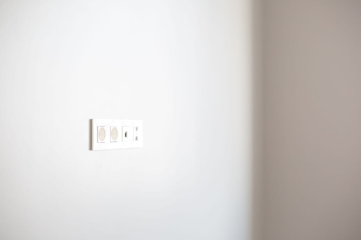 A white electrical socket on a plain wall.