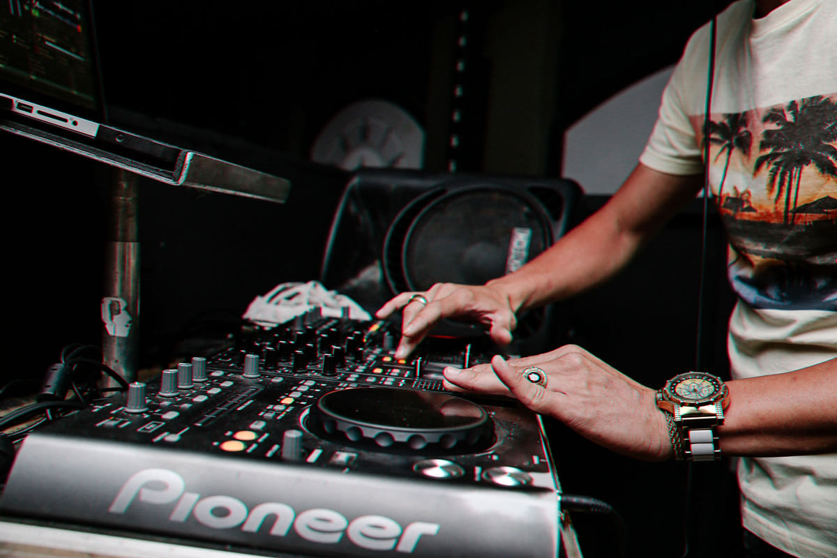 A DJ adjusting controls on a mixing desk.