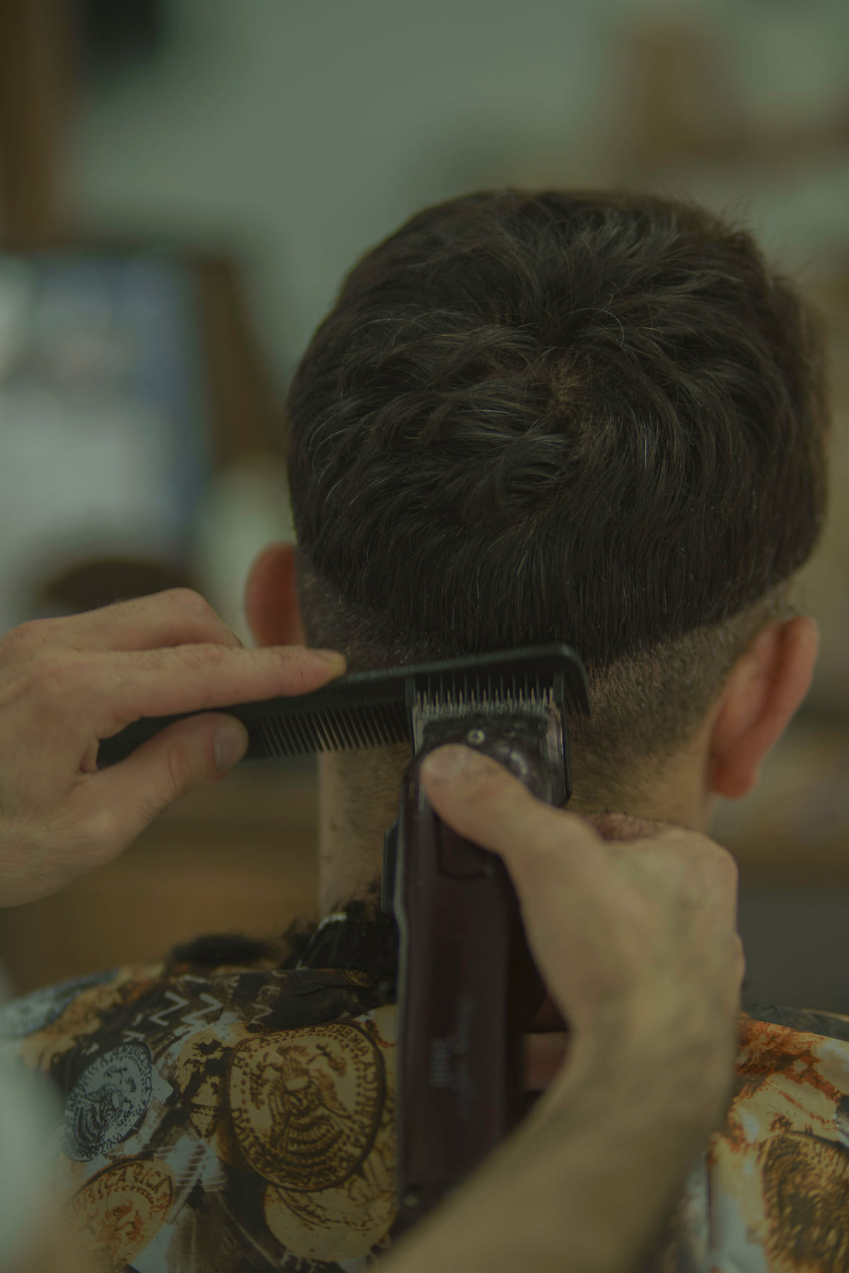 Hair clippers shaping the sides of a client's short haircut.