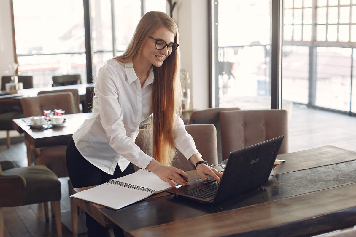 A businesswoman working on her laptop at a bright café table.