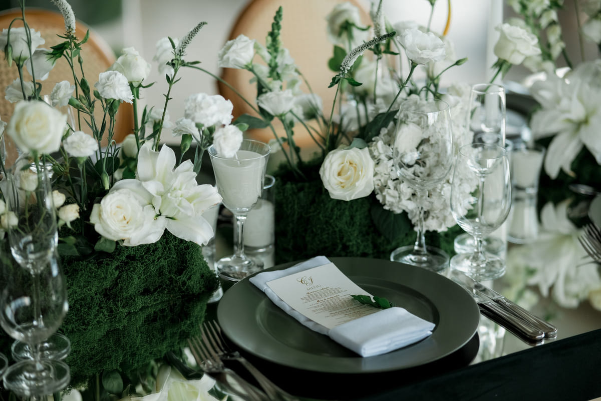 A wedding reception table arranged with white flowers and place settings.