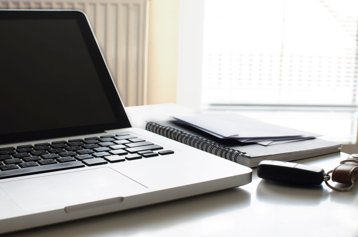 A laptop and open notebook on a bright desk.