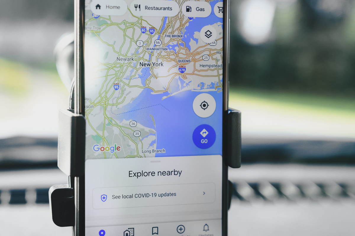 A smartphone mounted in a car with Google Maps displayed.