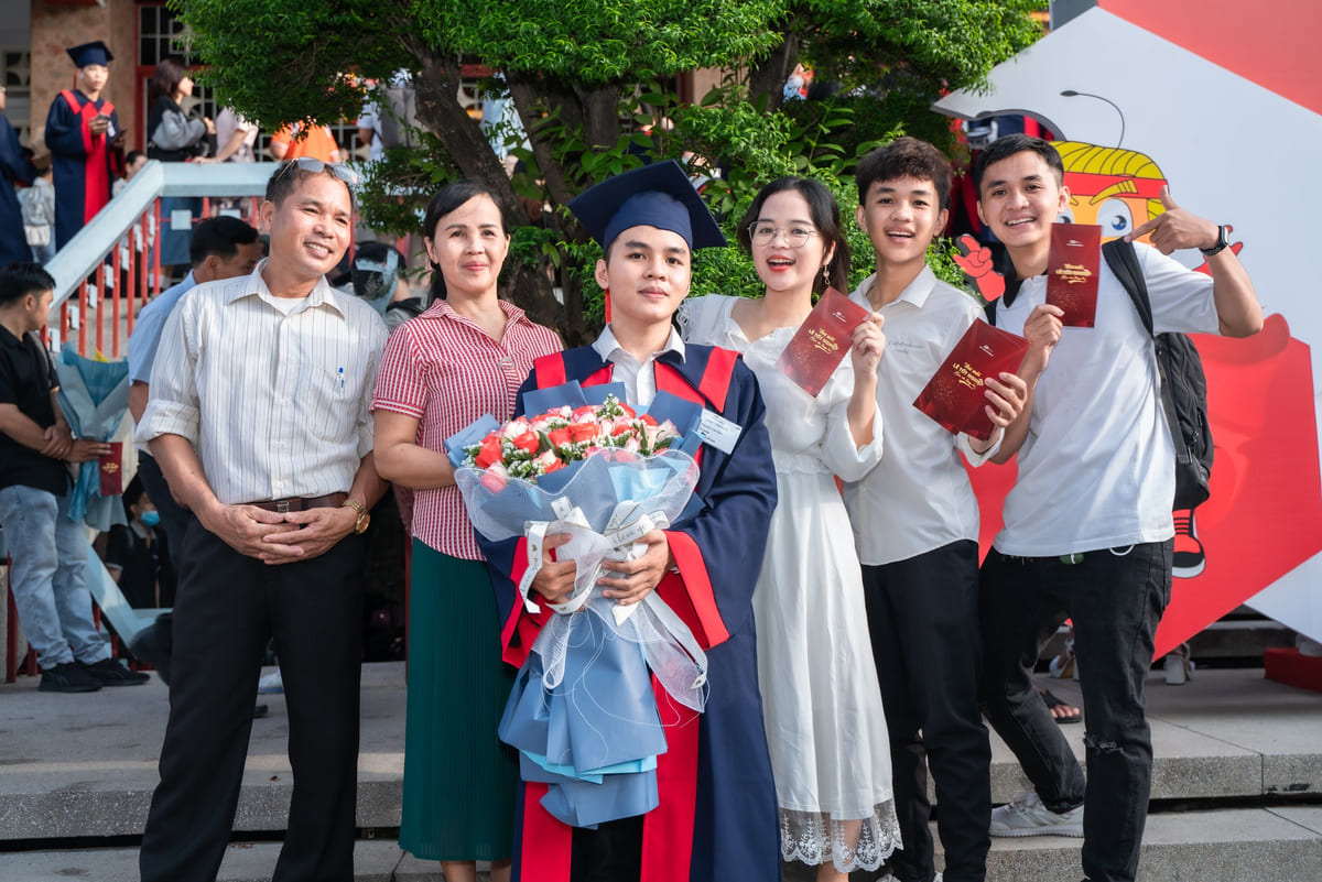 A graduate celebrating with family members outdoors.