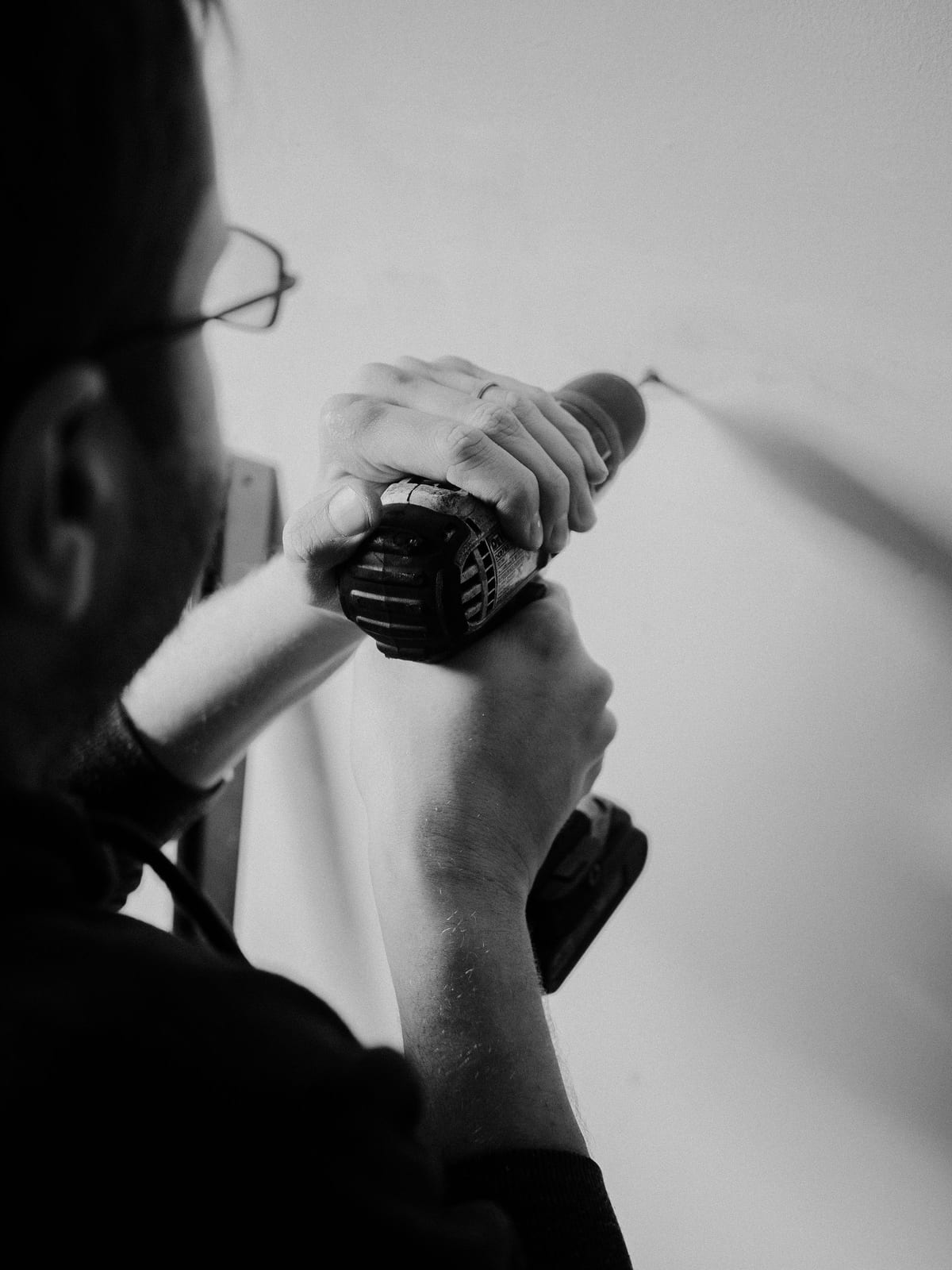 A close-up of a worker using a drill against a wall.