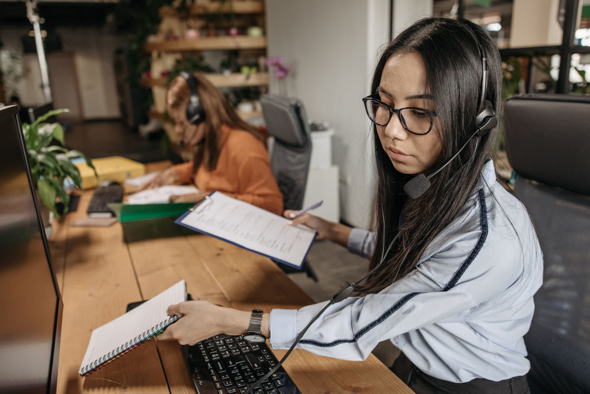 An office worker using a headset while reviewing notes.
