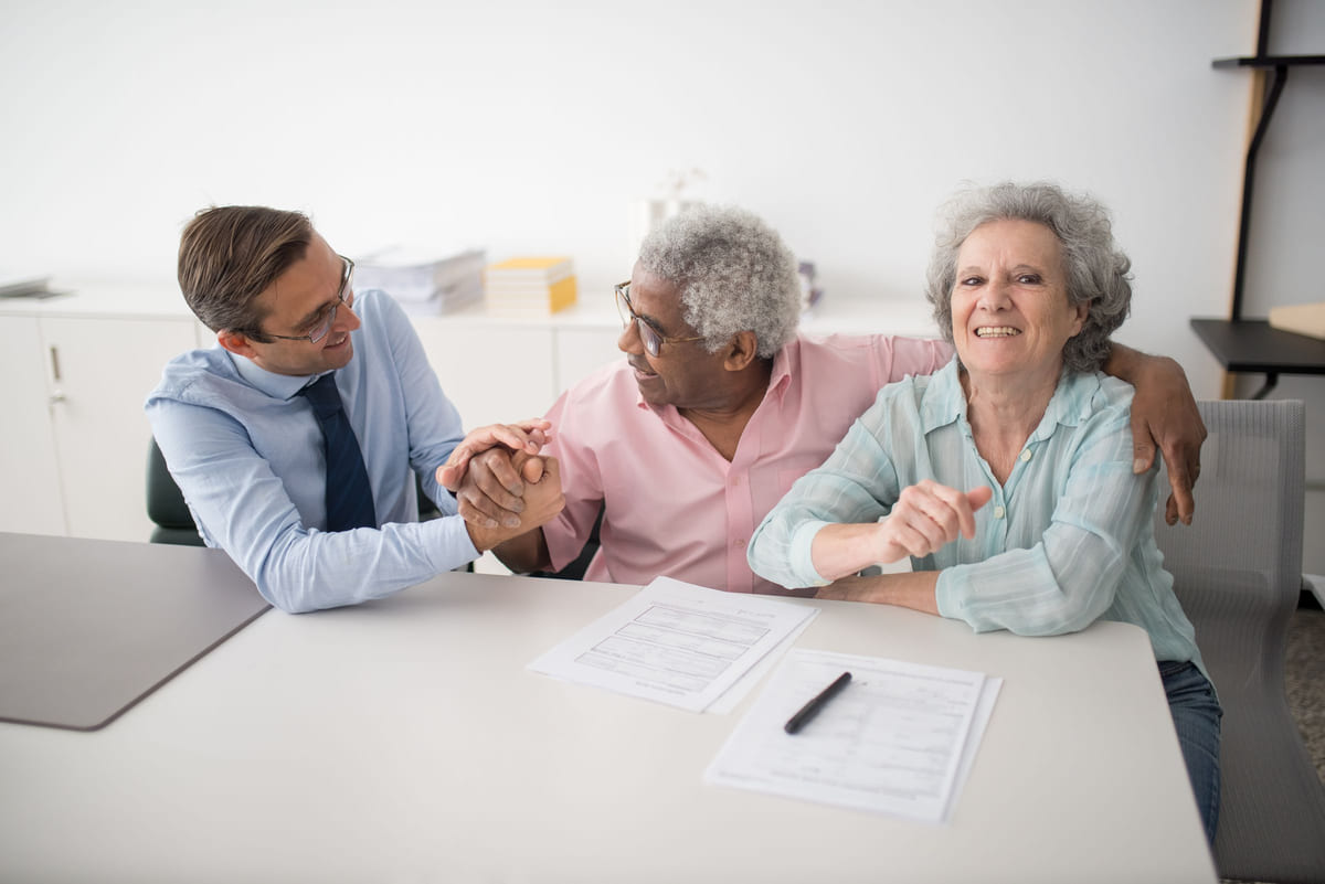 An adviser meeting with a smiling couple at a desk.