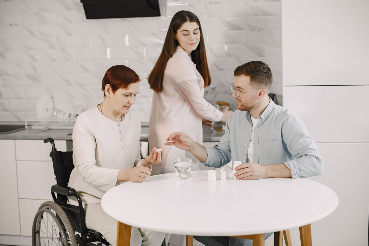Adult family members helping an older woman at a kitchen table.