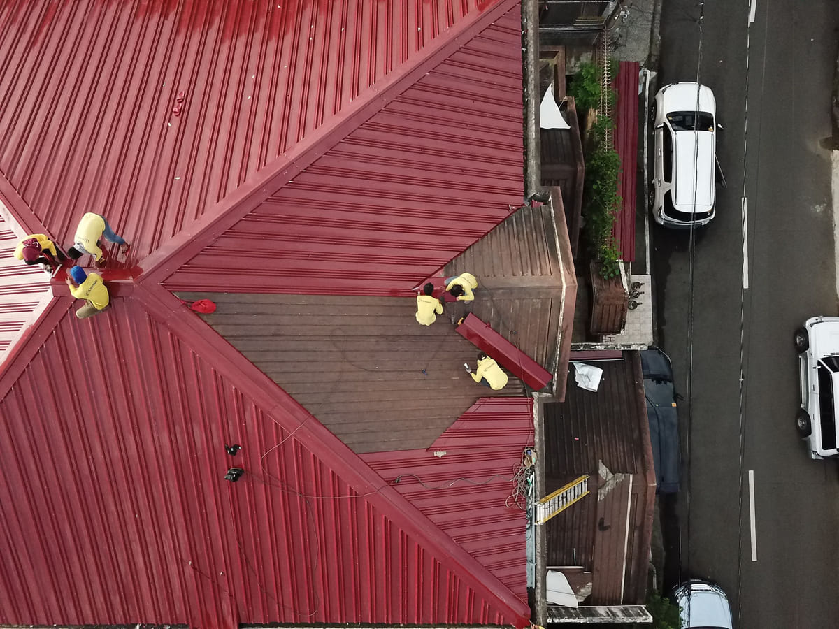 An overhead view of workers carrying out repairs on a house roof.